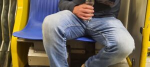 Person mit Jeans sitzt breitbeinig in der U-Bahn und belegt deshalb mehr als einen Sitz.